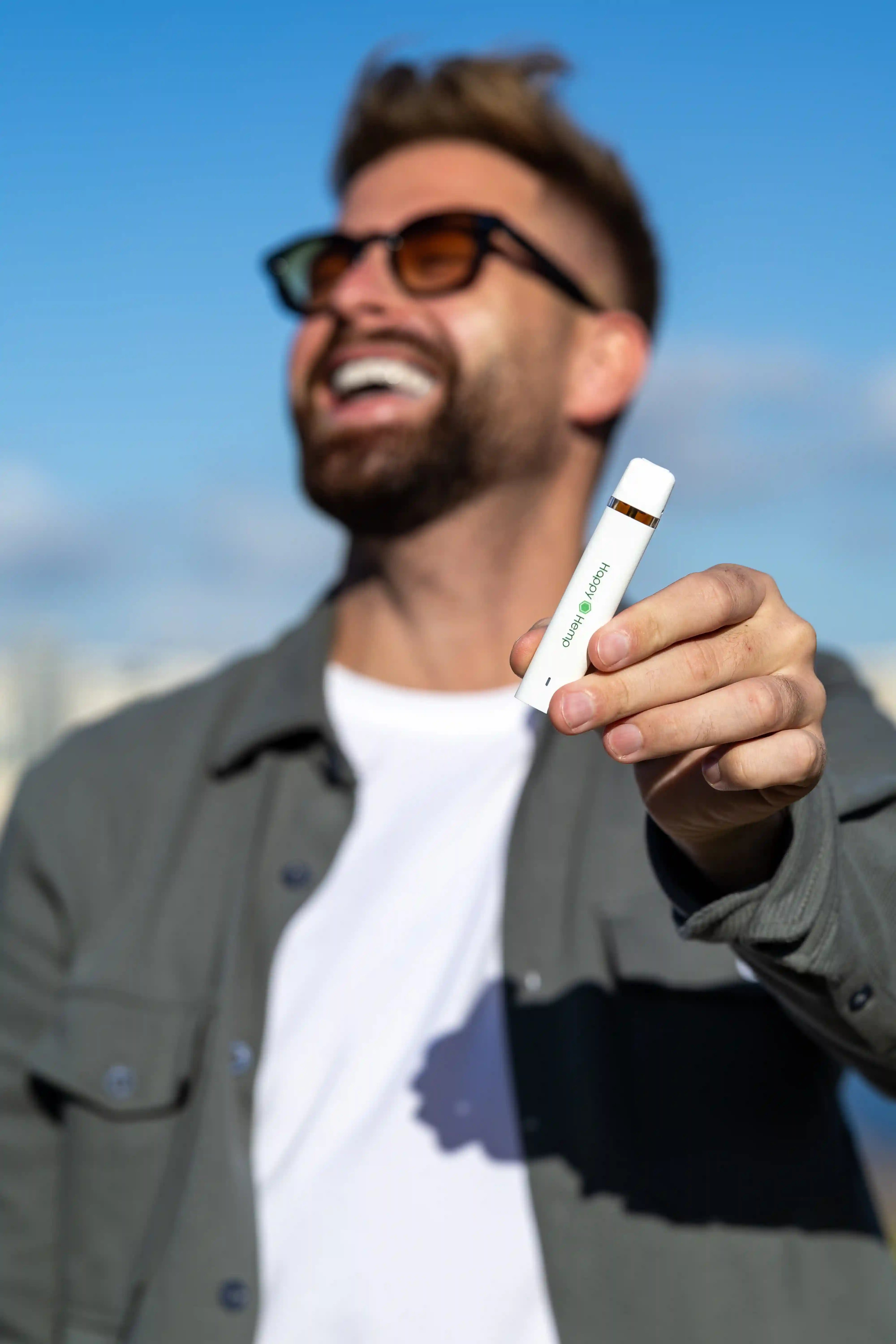 Ein lächelnder Mann mit Sonnenbrille hält den H3 Ultra Vape Pen in der Hand und streckt seinen Arm aus